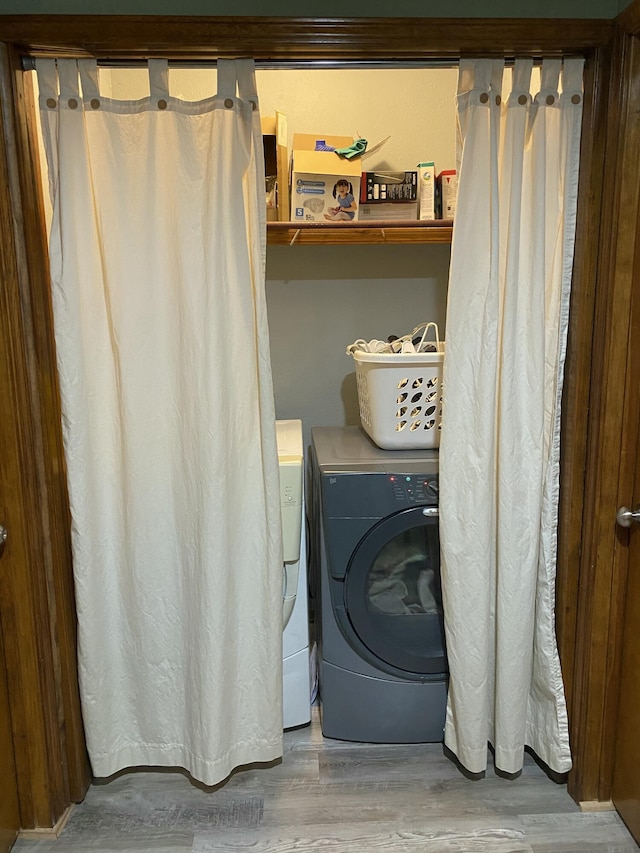 clothes washing area with washer / dryer, laundry area, and wood finished floors