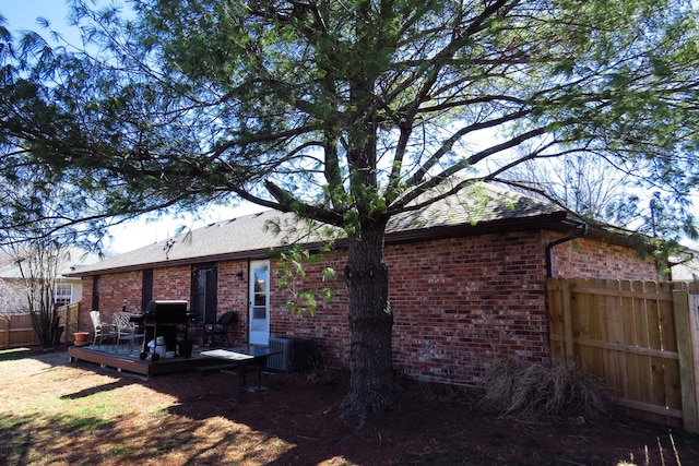 rear view of property featuring fence, a deck, and brick siding