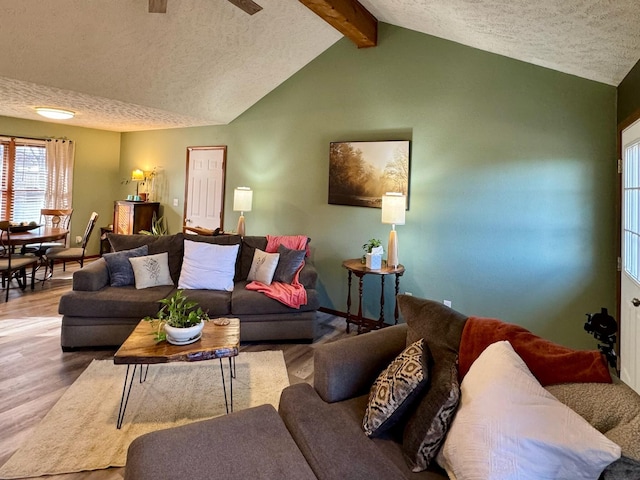 living room with vaulted ceiling with beams, a textured ceiling, and wood finished floors