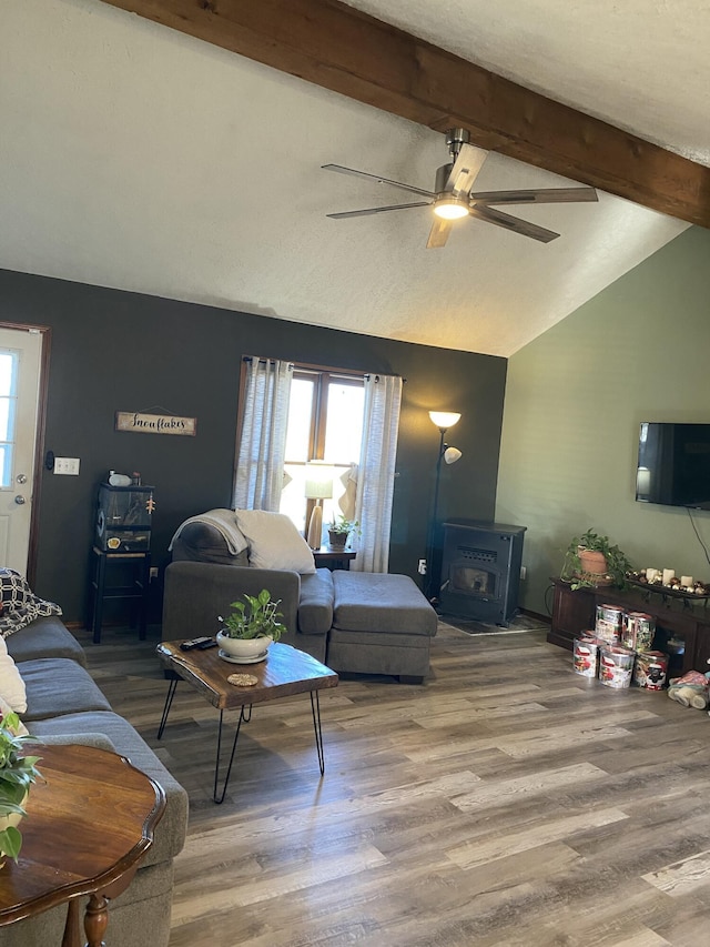 living room with a wealth of natural light, a wood stove, vaulted ceiling with beams, and wood finished floors