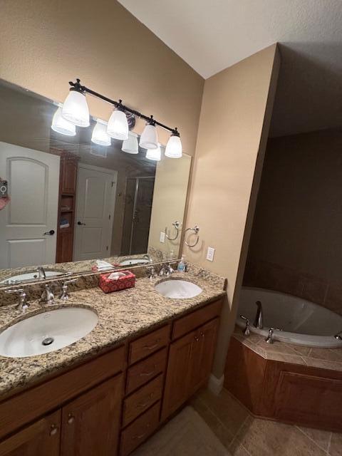 bathroom with double vanity, a sink, a bath, and tile patterned floors