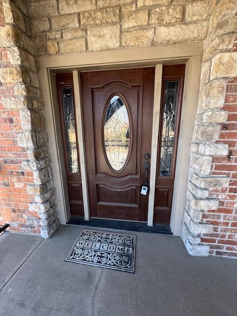 doorway to property featuring stone siding and brick siding