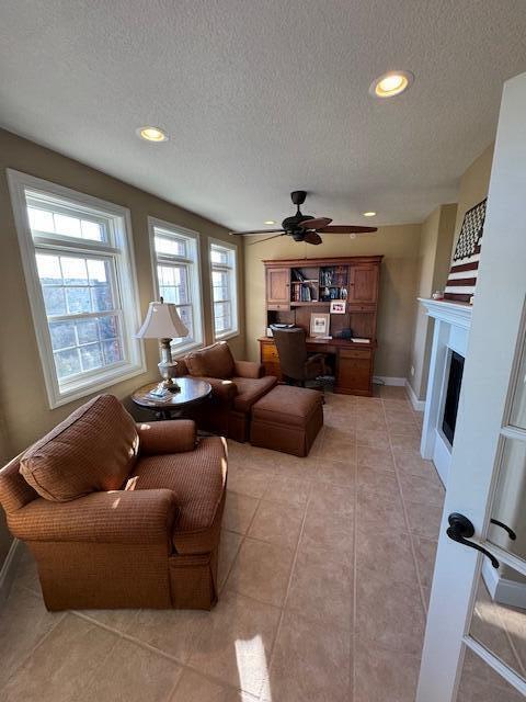 living area featuring a fireplace, light tile patterned floors, recessed lighting, ceiling fan, and baseboards