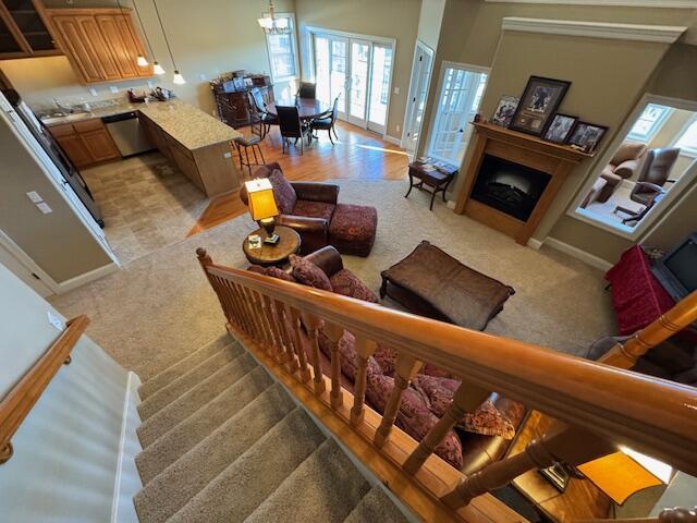 living room featuring stairs, a fireplace, carpet flooring, and a notable chandelier