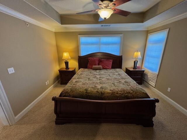 bedroom with baseboards, a tray ceiling, crown molding, and carpet flooring