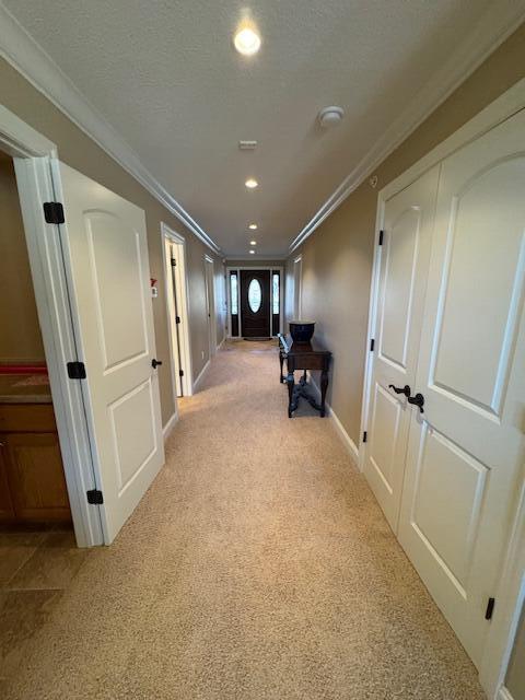 hallway featuring recessed lighting, light carpet, crown molding, and a textured ceiling