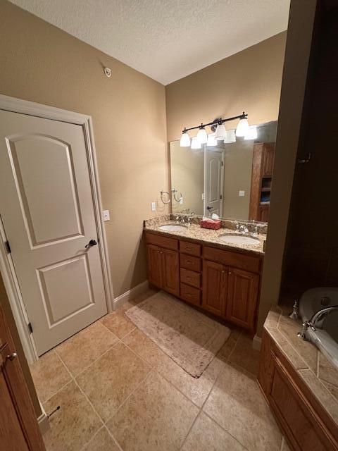 full bath with tile patterned flooring, a sink, a textured ceiling, and double vanity