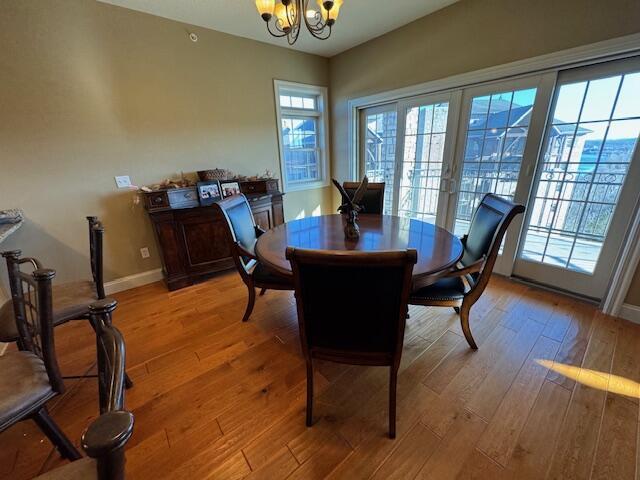 dining space featuring a chandelier, french doors, light wood finished floors, and baseboards