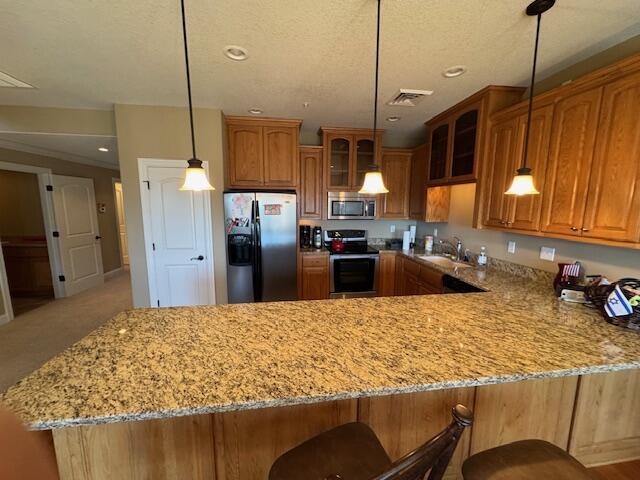 kitchen with glass insert cabinets, appliances with stainless steel finishes, brown cabinetry, and a sink