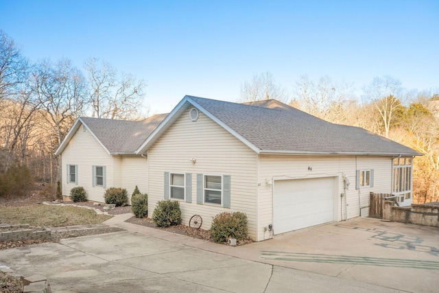 view of front of house with driveway, an attached garage, and a shingled roof