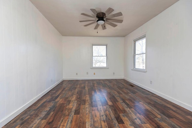 empty room with ceiling fan, dark wood finished floors, and baseboards