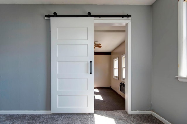 unfurnished room featuring carpet floors, a barn door, a wall unit AC, and baseboards