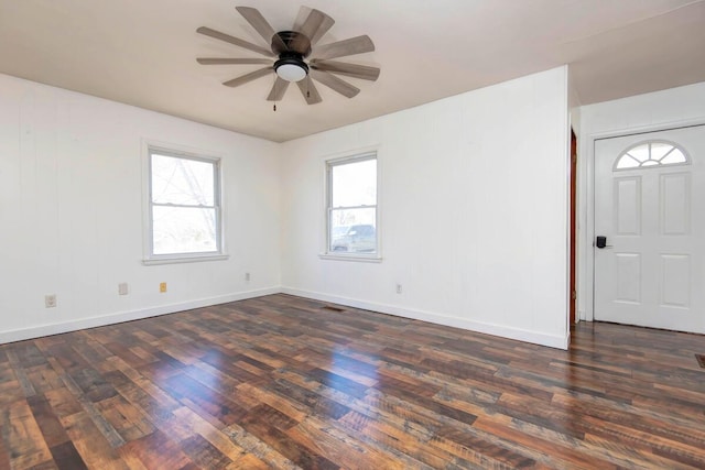 unfurnished room featuring dark wood-style flooring, a healthy amount of sunlight, and baseboards