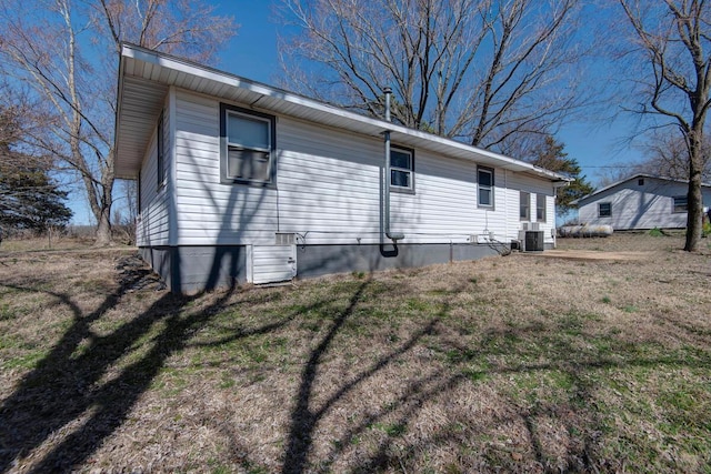 view of side of home featuring central AC and a yard