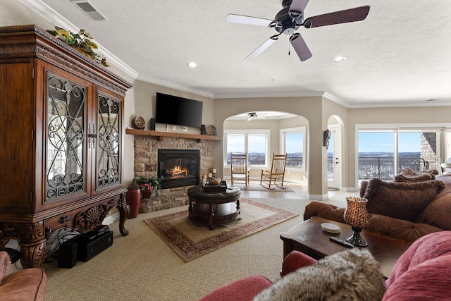 living room with arched walkways, a fireplace, visible vents, ornamental molding, and a textured ceiling