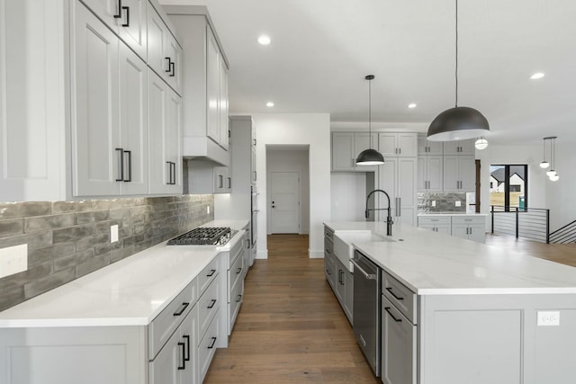 kitchen featuring stainless steel appliances, recessed lighting, a sink, wood finished floors, and a large island with sink