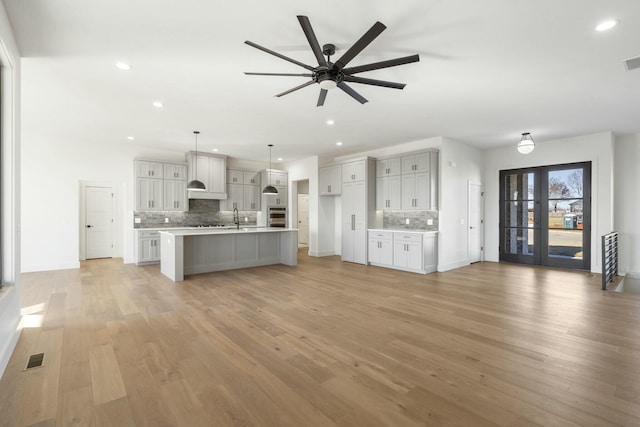 unfurnished living room featuring light wood-style floors, recessed lighting, french doors, and visible vents