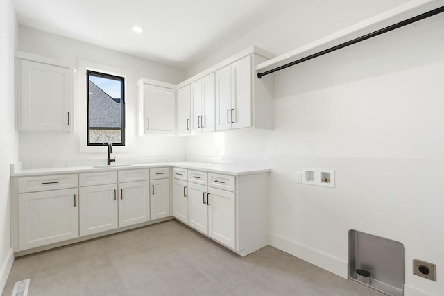 clothes washing area with hookup for an electric dryer, washer hookup, a sink, visible vents, and cabinet space