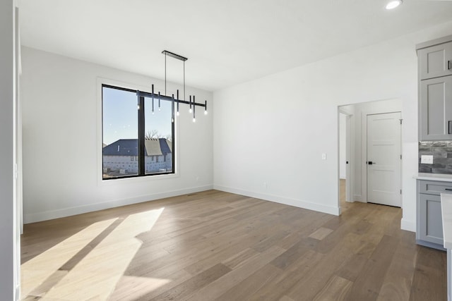 unfurnished dining area featuring light wood-type flooring, baseboards, and recessed lighting