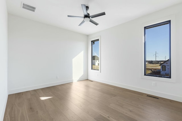 spare room with visible vents, ceiling fan, baseboards, and wood finished floors