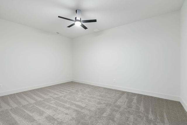 carpeted spare room with a ceiling fan and baseboards