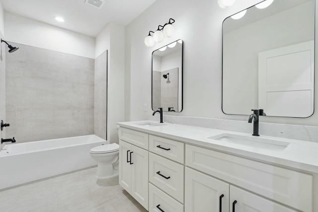 bathroom with visible vents, double vanity, a sink, and toilet