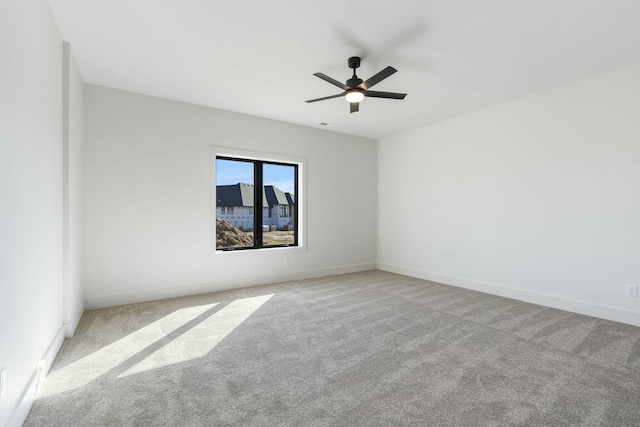 carpeted empty room featuring ceiling fan and baseboards