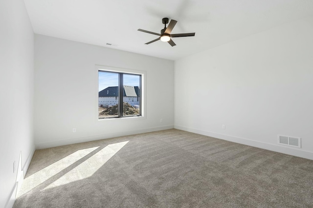 empty room featuring ceiling fan, carpet floors, visible vents, and baseboards