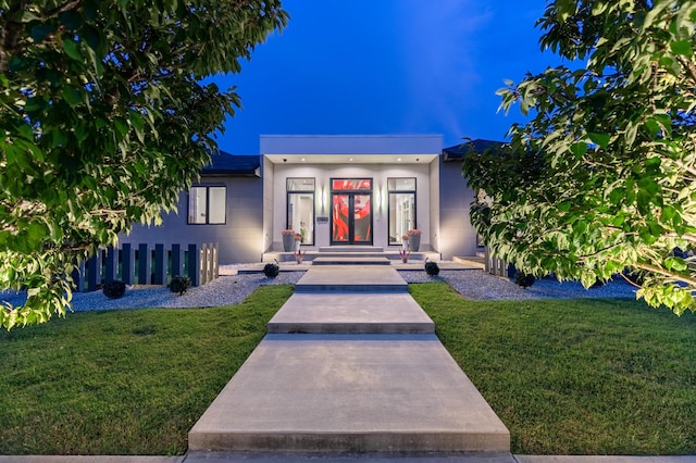 property entrance featuring a yard and stucco siding