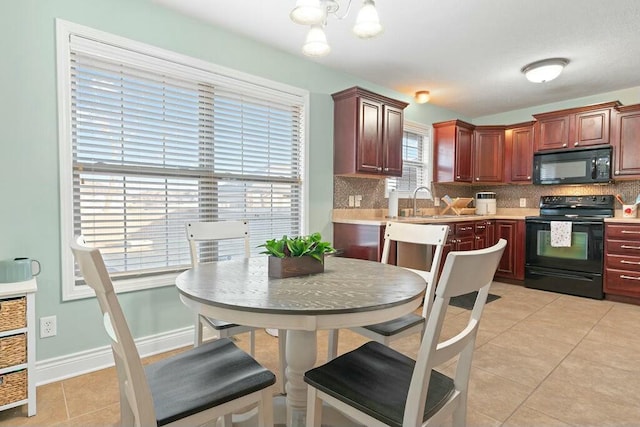 kitchen featuring light tile patterned floors, baseboards, light countertops, black appliances, and backsplash