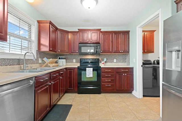 kitchen with light tile patterned floors, a sink, dark brown cabinets, independent washer and dryer, and black appliances