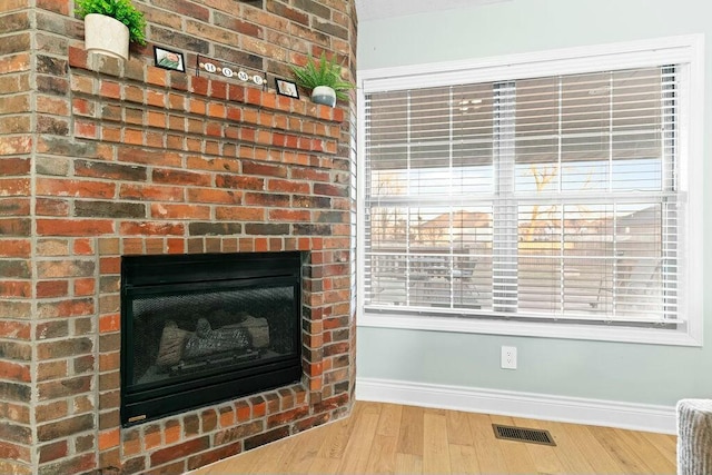 interior details featuring visible vents, a fireplace, baseboards, and wood finished floors