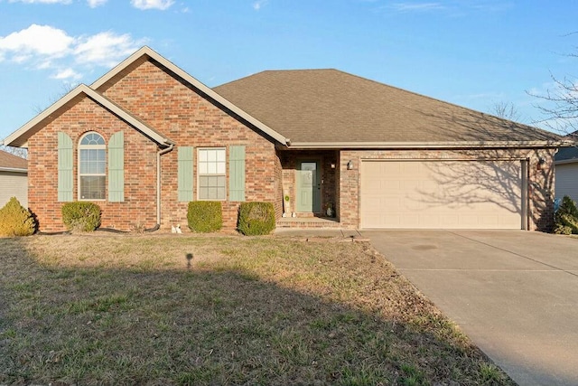 ranch-style home featuring brick siding, a shingled roof, concrete driveway, an attached garage, and a front yard