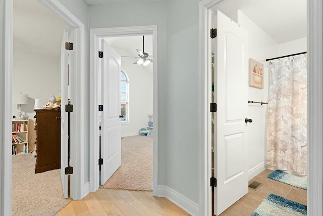 hall featuring light wood-style floors, baseboards, and visible vents