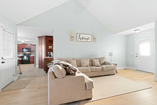 living area featuring high vaulted ceiling, baseboards, and light wood finished floors