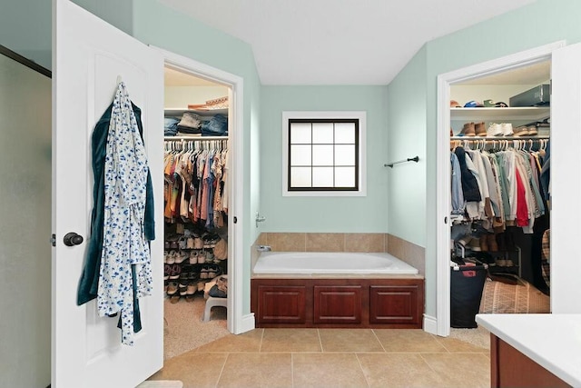 bathroom featuring a spacious closet, vanity, a bath, and tile patterned floors