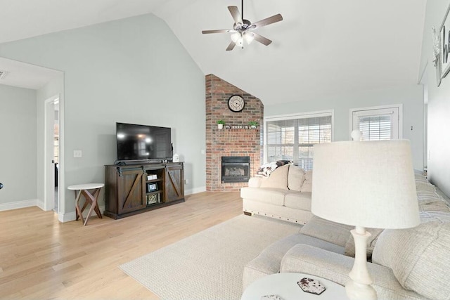 living area with ceiling fan, high vaulted ceiling, wood finished floors, baseboards, and a brick fireplace