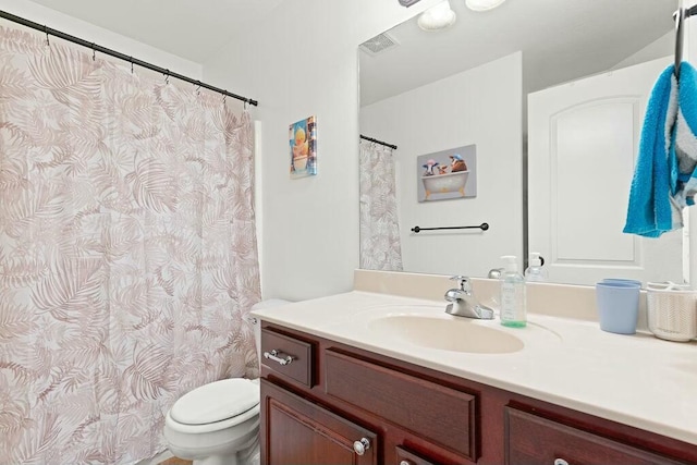 bathroom with toilet, vanity, and visible vents