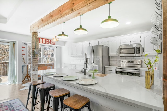 kitchen featuring light stone counters, stainless steel appliances, white cabinetry, backsplash, and beam ceiling