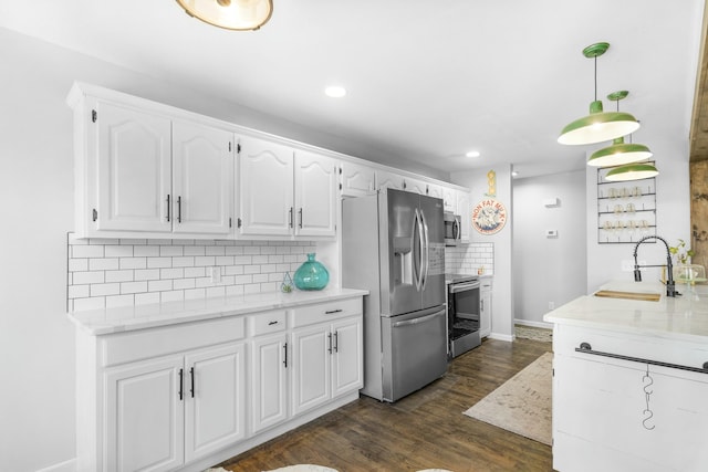 kitchen with dark wood finished floors, stainless steel appliances, decorative backsplash, white cabinets, and a sink