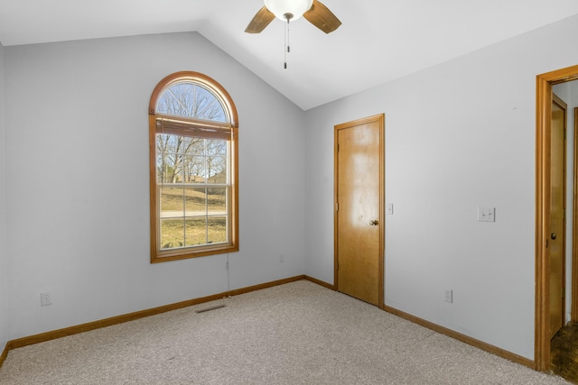 spare room with baseboards, visible vents, lofted ceiling, ceiling fan, and carpet flooring