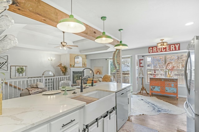 kitchen featuring wood finished floors, appliances with stainless steel finishes, a sink, and white cabinets