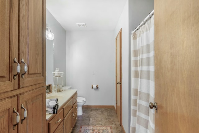 full bath featuring toilet, vanity, visible vents, baseboards, and stone finish flooring