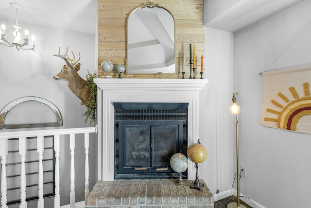 details featuring a glass covered fireplace, a notable chandelier, and baseboards