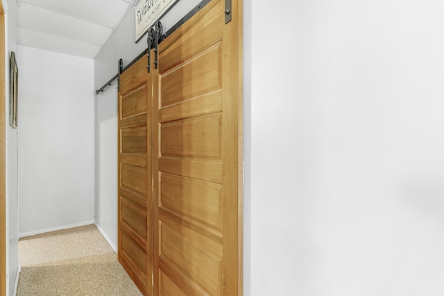 corridor with baseboards and a barn door