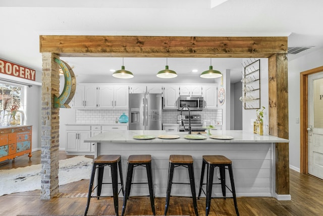 kitchen with stainless steel appliances, dark wood-style flooring, white cabinets, and a kitchen breakfast bar