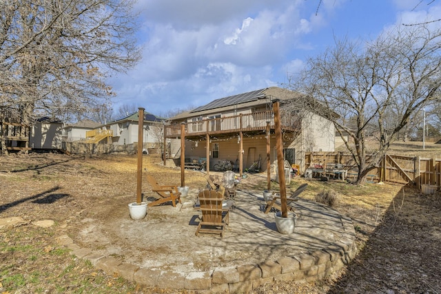 back of house featuring solar panels, an outbuilding, a gate, fence, and a wooden deck