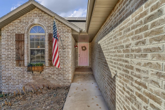 doorway to property featuring solar panels and brick siding