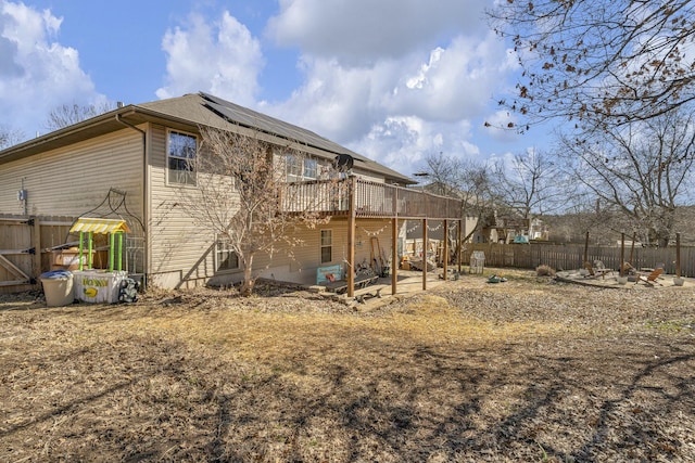 rear view of house featuring a fenced backyard, a patio, a deck, and solar panels