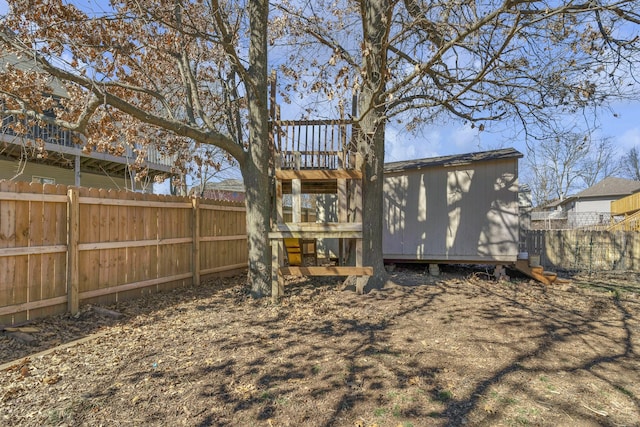 rear view of property featuring a storage unit, an outdoor structure, and a fenced backyard